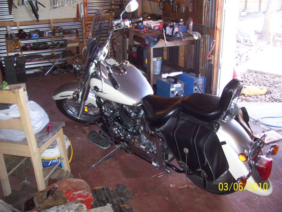 Silver and white motorcycle with black saddlebags parked in a garage