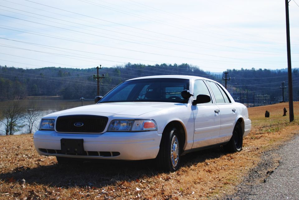 White 2002 Ford Crown Victoria sedan parked on a dry, grassy roadside
