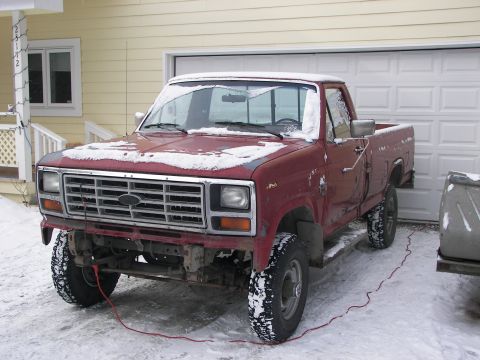 1990 Chevrolet Suburban - A red pickup truck sits in the snow, showing its front grille and side profile.