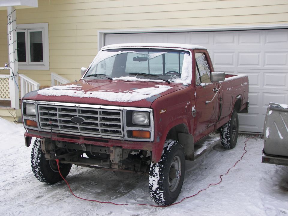 Red pickup truck with snow, front grille visible