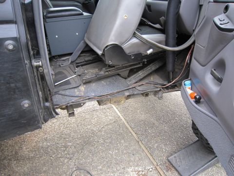 1996 Ford Bronco - The interior of a vehicle is shown, focusing on the floor area near the driver's side door and seat.