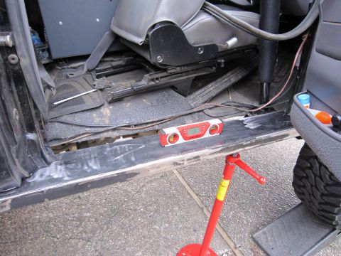 1996 Ford Bronco - A digital level rests on the rocker panel inside a vehicle, with the floor and seats visible.