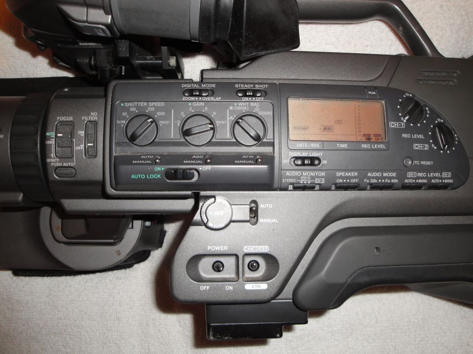 Close-up of video camera controls including focus, shutter speed, gain, white balance, and audio settings