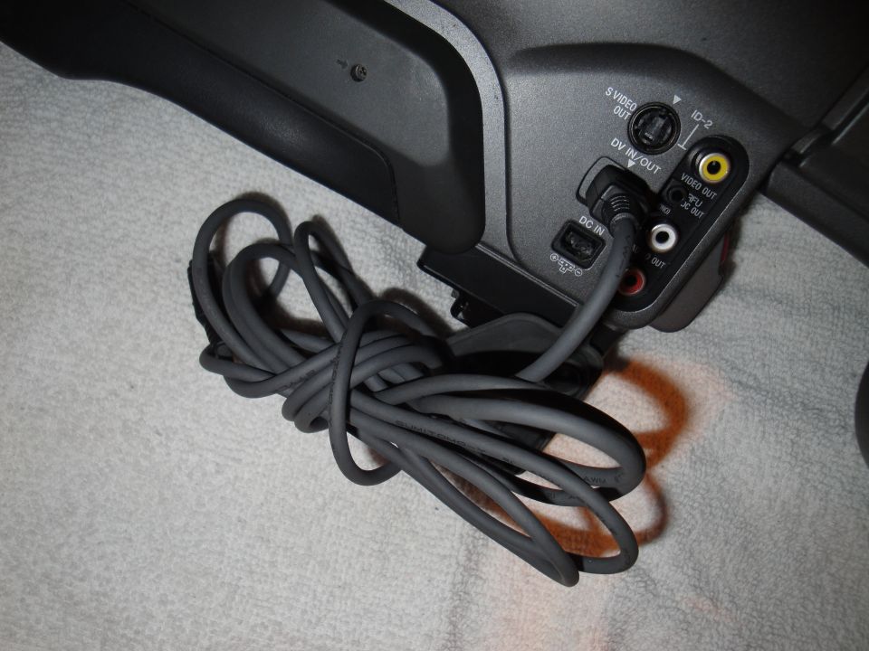 Camcorder ports labeled S VIDEO OUT, DV IN/OUT, DC IN, and VIDEO OUT, with a coiled gray cable plugged into DC IN