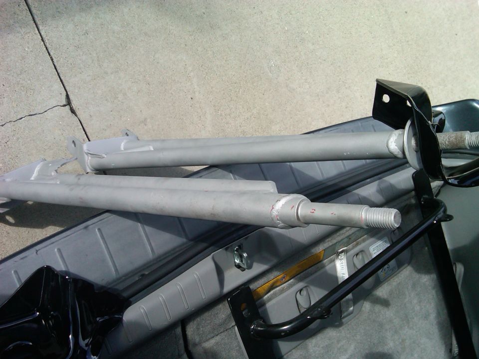 Two gray radius arms with threaded ends and black mounting brackets