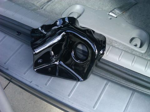 1986 Ford Bronco - A black metal suspension part is placed on the interior floor of a vehicle.