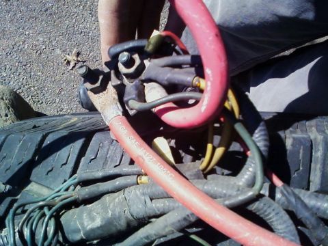 1990 Ford Bronco - A close-up view of automotive electrical wiring and a battery terminal, with a red cable marked '2 GA SAE J127 105°C'.