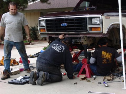 1982 Ford Bronco - Three men work on the front end of a maroon and tan Ford truck, which appears to be from the early 1980s.