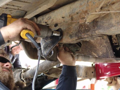 1982 Ford Bronco - Mechanics are seen working on the undercarriage of a vehicle, utilizing an impact wrench for what appears to be a lift or suspension modifi…