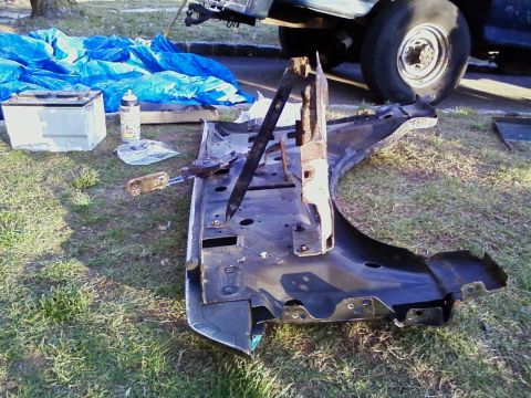 1990 Ford Bronco - A disassembled car fender assembly lies on the grass next to a battery and blue tarp.