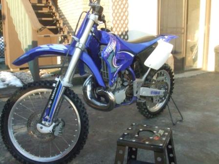 1996 Ford Bronco - A blue Yamaha dirt bike is parked outdoors, resting on a stand.