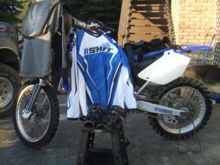 1996 Ford Bronco - A dirt bike is parked next to a truck, adorned with motocross apparel and gear.