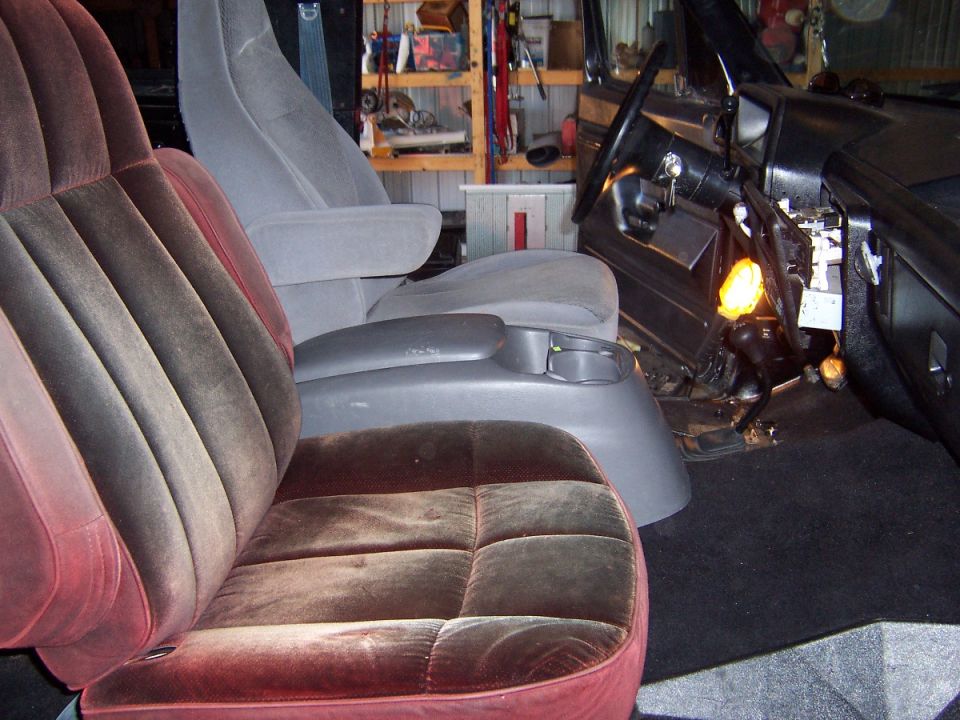 Mixed truck seats, gray and burgundy velour, in a garage