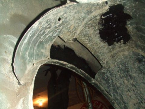 1996 Ford Bronco - The interior of a vehicle's wheel well shows dirt, grime, and a patch of black sealant.