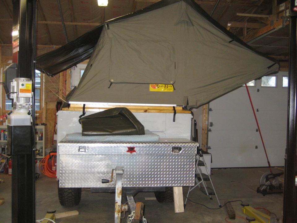 Trailer with pop-up tent raised, diamond plate toolbox, and green cover