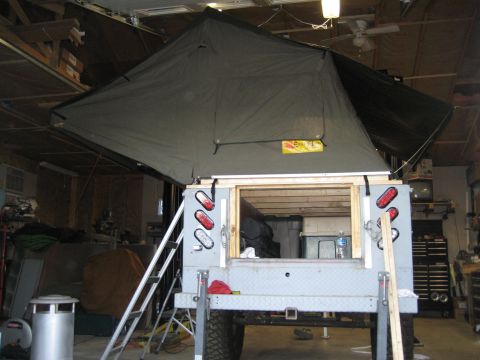 1996 Ford Bronco - Rooftop tent setup on a truck bed, viewed from the rear, inside a garage.