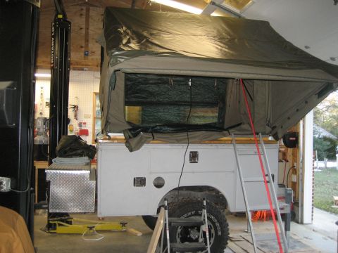 1996 Ford Bronco - A truck is parked inside a garage, fitted with a large pop-up camper tent.