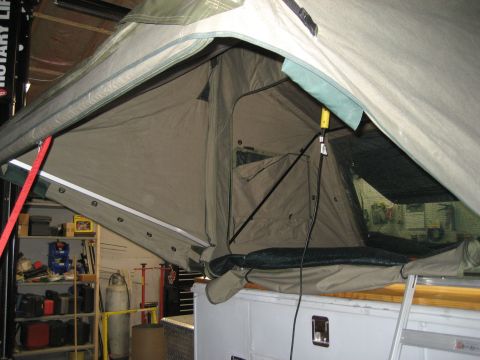 1996 Ford Bronco - Interior view of an open roof top tent, showing its canvas construction and support poles, mounted on a vehicle.