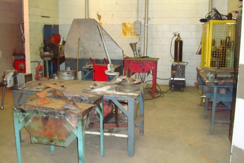 1996 Ford Bronco - A cluttered workshop scene with various tools and equipment, including welding gear and workbenches.
