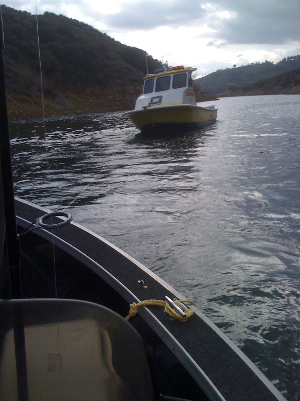 White and yellow boat on a lake with hills in background