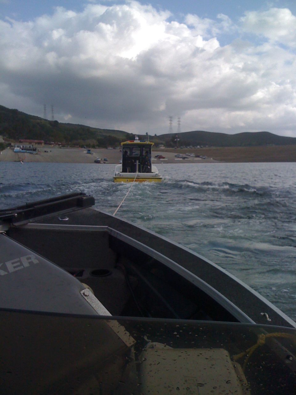 Yellow and black tugboat being towed on the water
