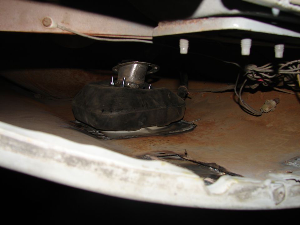 Underside of a vehicle showing a black rubber boot and metal assembly with wires
