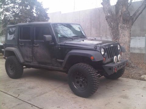 2008 Jeep Wrangler - Black Jeep Wrangler parked on concrete with aftermarket bumper and large tires.