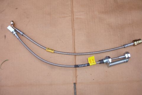 1995 Ford Taurus - Two stainless steel brake lines are laid out on a brown surface, with yellow labels indicating their purpose.