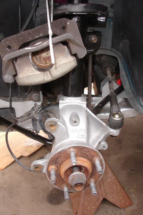 1995 Ford Taurus - Front suspension knuckle with brake caliper and tie rod end. Part number LGS 071 is visible.