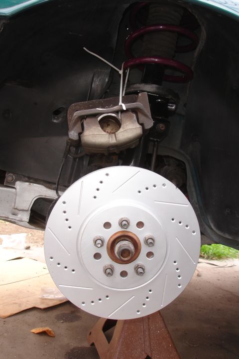 1995 Ford Taurus - Car brake rotor and caliper assembly shown on a jack stand.