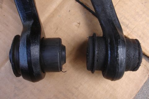 1995 Ford Taurus - Close-up view of two automotive control arm bushings, one showing signs of wear and tear.