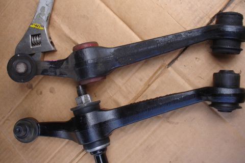 1995 Ford Taurus - Close-up of automotive control arms with a wrench, likely for repair or replacement.