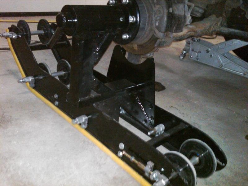 Black steel fabricated fixture holding an axle assembly on a garage floor