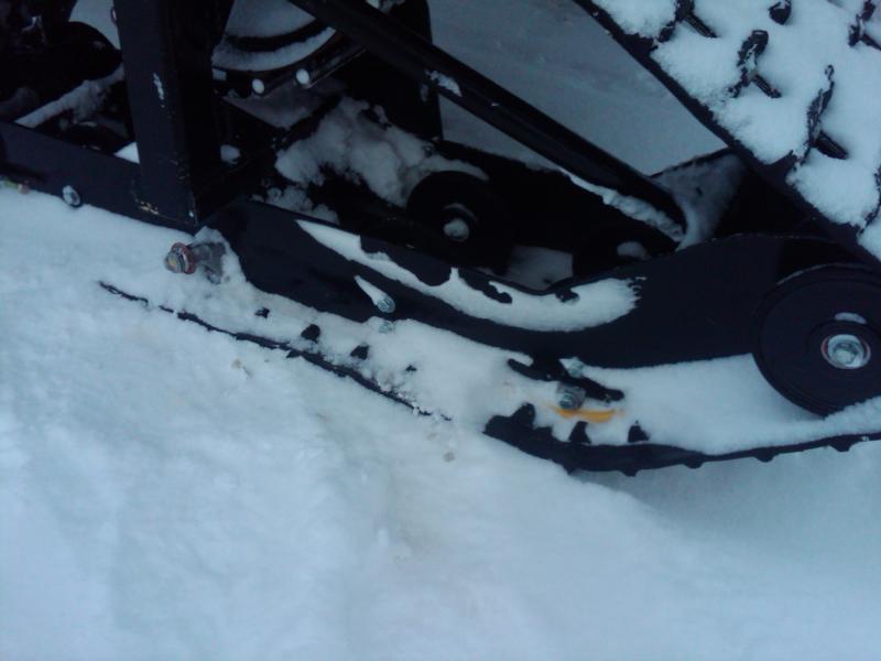 Snow-covered snowmobile track and idler wheels close-up