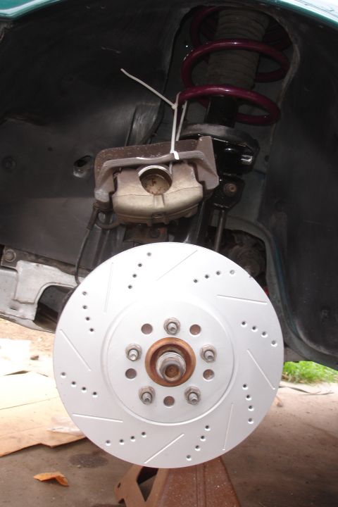 1995 Ford Taurus - A drilled and slotted brake rotor is mounted on a vehicle's hub, with the brake caliper positioned above it.