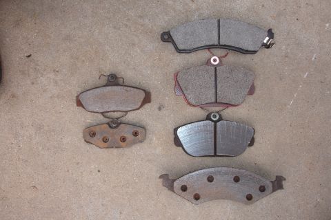 1995 Ford Taurus - Various brake pads are displayed on concrete, some appearing new and others showing signs of age and use.