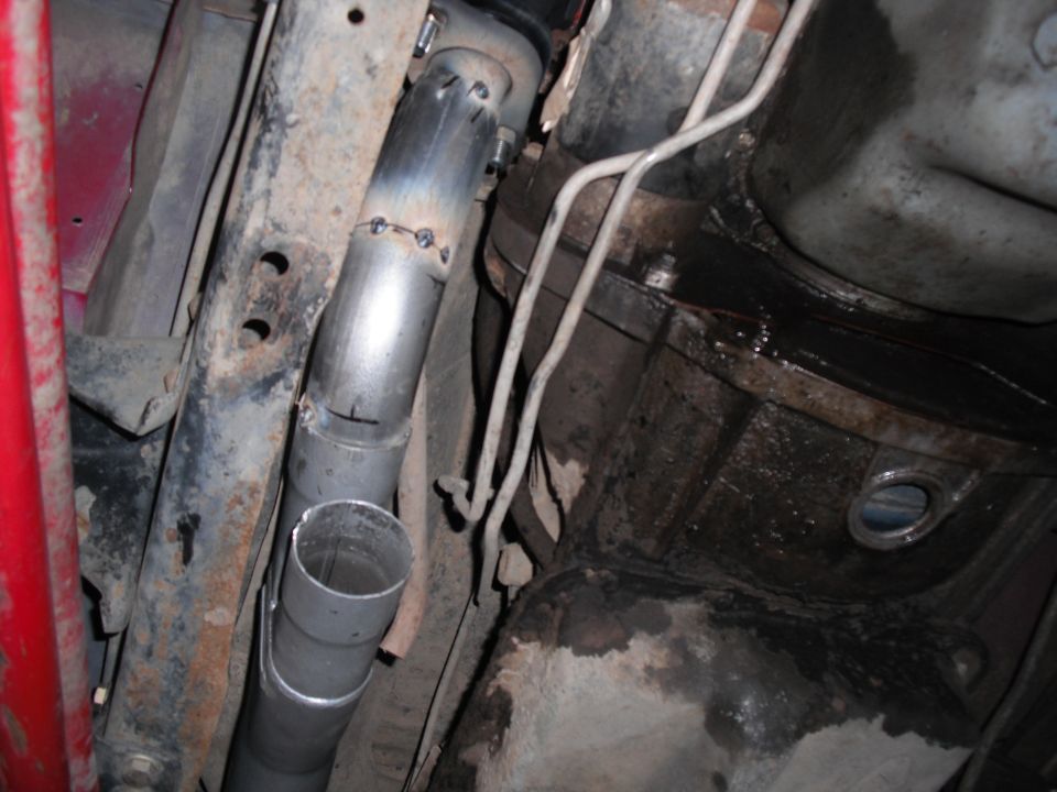 underneath view of a vehicle's custom exhaust pipe being welded and installed
