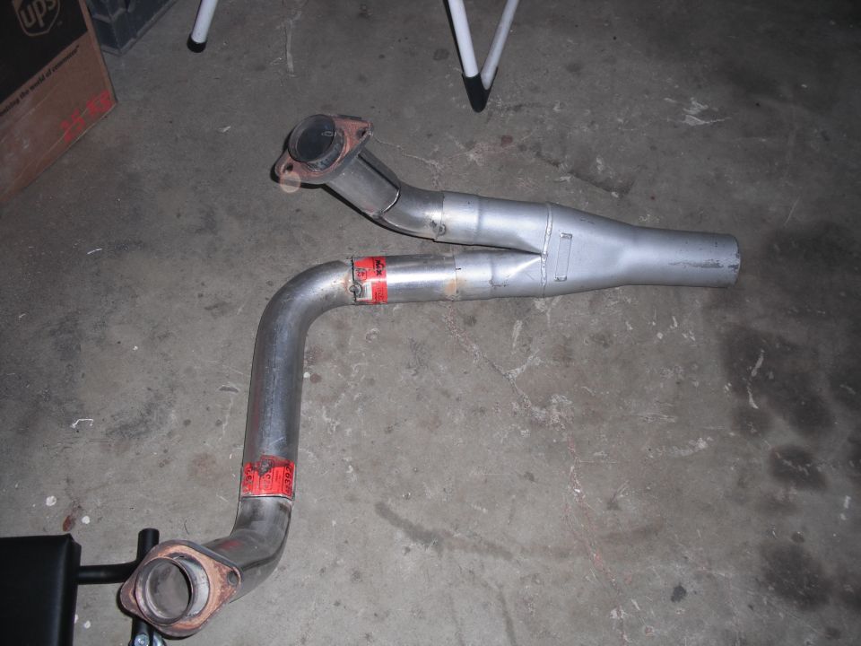 Exhaust y-pipe with red markings and flange connections on a concrete floor