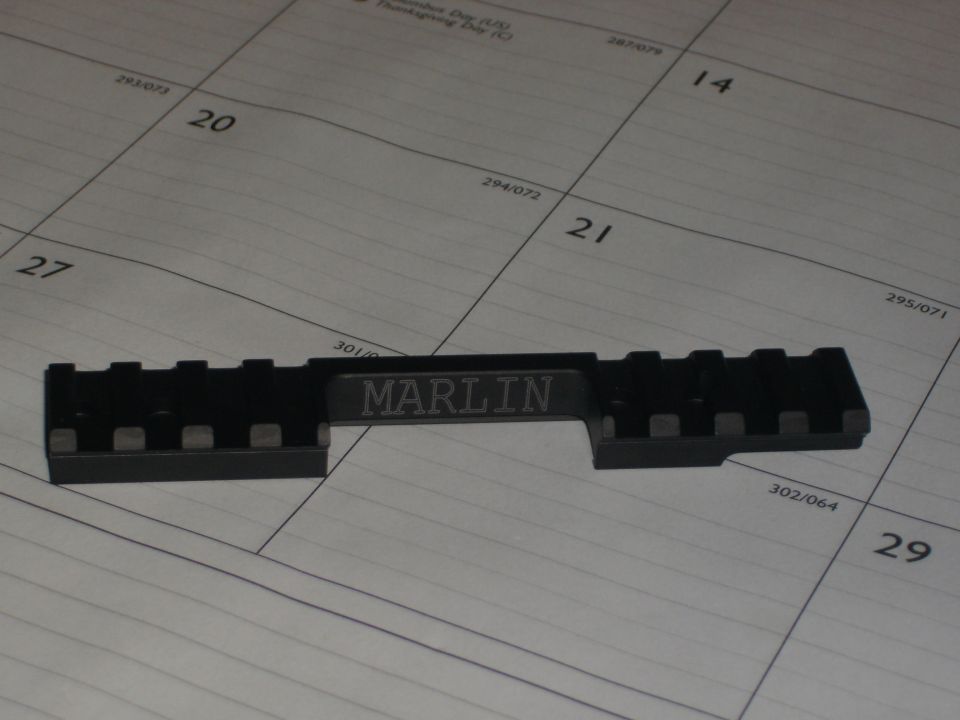 Black Marlin scope mount rail resting on a paper calendar