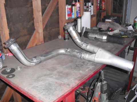 1991 Ford Bronco - A custom-fabricated exhaust y-pipe assembly rests on a workbench in a garage setting.