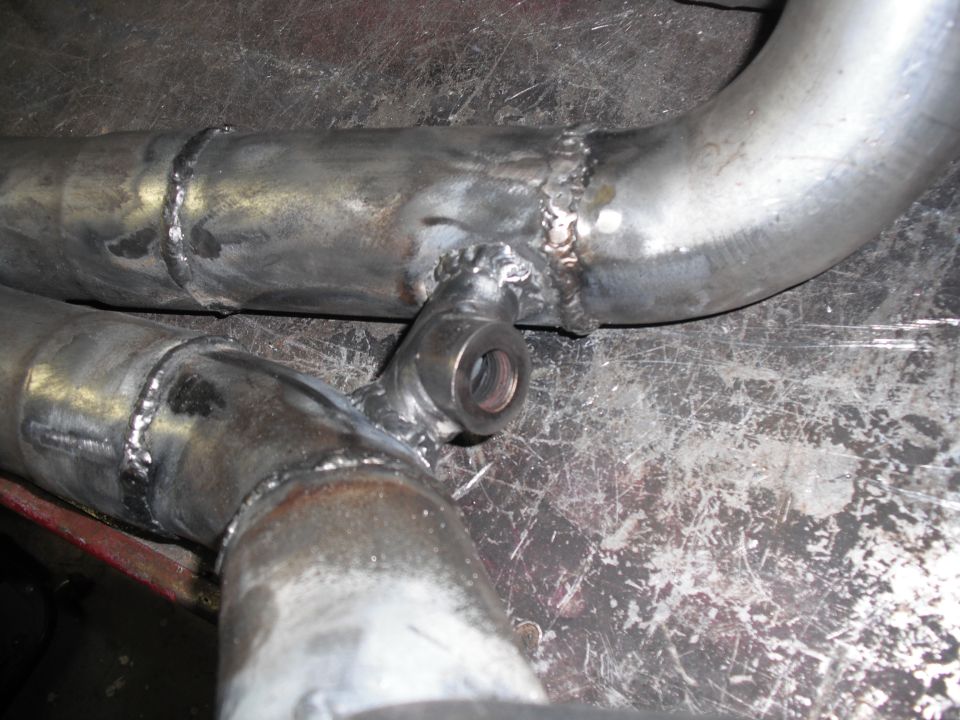 Close-up of a custom exhaust pipe with a T-junction and threaded fitting