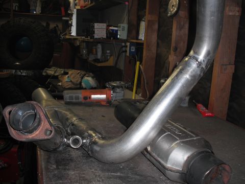 1991 Ford Bronco - A custom exhaust y-pipe and catalytic converter are shown on a workbench in a garage setting.