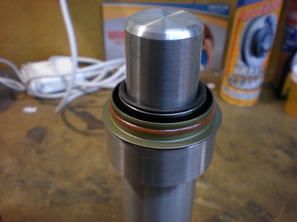 Machined shaft end with seal and O-ring standing on workbench next to brake cleaner
