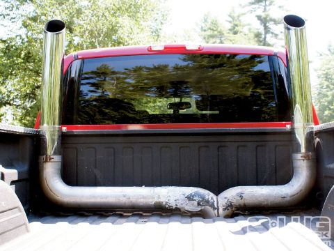 1990 Ford Bronco - Dual exhaust pipes are installed in the bed of a red pickup truck.