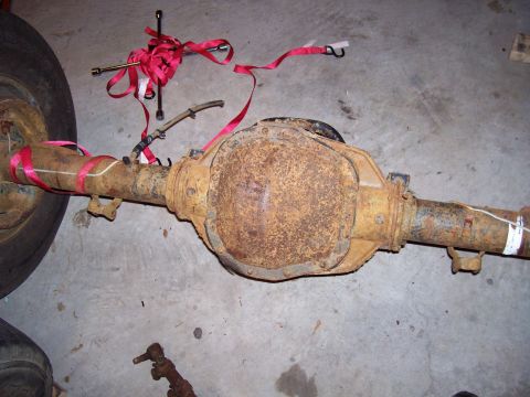 1994 Ford Bronco - A heavily rusted rear axle assembly is secured with red tie-down straps and a socket wrench.