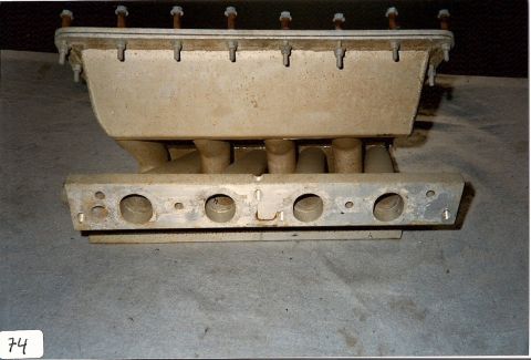 1973 Ford Mustang - A close-up view of an engine intake manifold, showing its internal structure and mounting points.