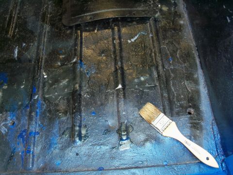 1978 Jeep CJ5 - A paintbrush lies on the floor pan of a vehicle, which appears to be undergoing some form of repair or painting.