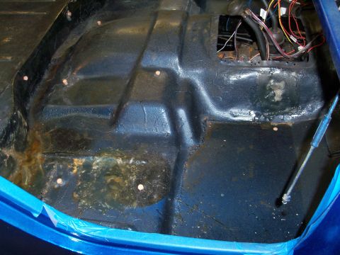 1978 Jeep CJ5 - The interior floor of a blue vehicle shows signs of rust and exposed wiring, with blue tape along the edges.