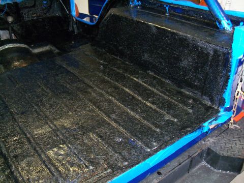 1978 Jeep CJ5 - The interior floor of a vehicle has been coated with a textured black material, likely for protection.
