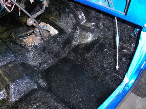 1978 Jeep CJ5 - Interior floor of a vehicle treated with black spray-on bedliner, revealing the transmission tunnel and shifter mechanism.